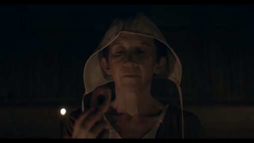 Close-up of the 60+ woman in the 18th-century film 'Thysia,' contemplating a potentially poisoned cookie, color graded and edited for post-production perfection.